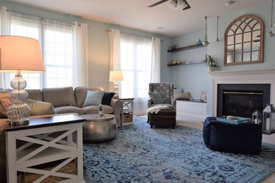 Modelo de sala de estar abierta costera de tamaño medio con paredes azules, moqueta, todas las chimeneas, marco de chimenea de madera y televisor colgado en la pared