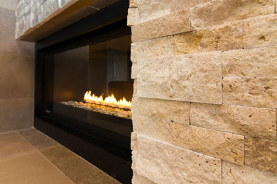 ポートランドにあるコンテンポラリースタイルのおしゃれなファミリールーム (石材の暖炉まわり) の写真