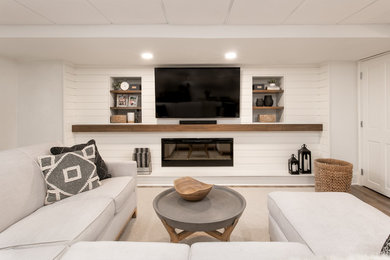 Imagen de sala de estar cerrada tradicional de tamaño medio con paredes blancas, suelo laminado, chimeneas suspendidas, marco de chimenea de madera, televisor colgado en la pared y suelo marrón