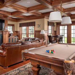 Imagen de sala de juegos en casa costera, extra grande, con paredes beige, suelo de madera en tonos medios, chimenea tradicional y televisor colgado en la pared