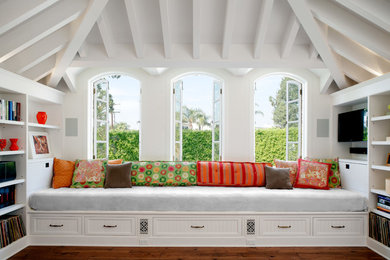 This is an example of a traditional games room in Los Angeles with white walls, medium hardwood flooring and a wall mounted tv.