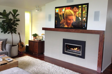 Modelo de sala de estar moderna de tamaño medio con paredes blancas, suelo de madera en tonos medios, chimenea lineal, televisor colgado en la pared y suelo marrón
