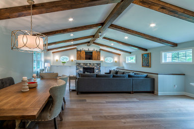 Example of a large trendy open concept light wood floor family room design in Minneapolis with beige walls, a standard fireplace, a stone fireplace and a concealed tv