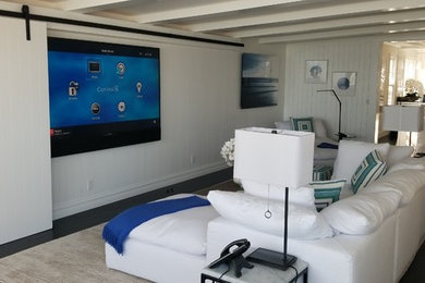 Diseño de sala de estar costera de tamaño medio con paredes blancas, suelo de madera oscura, todas las chimeneas y televisor colgado en la pared