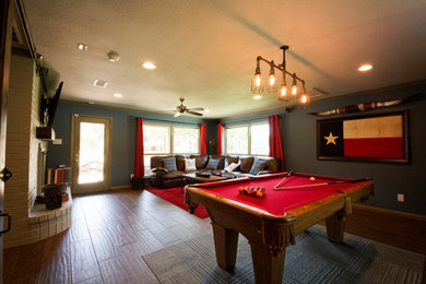 Ejemplo de sala de juegos en casa cerrada tradicional grande con paredes verdes, suelo laminado, todas las chimeneas, marco de chimenea de ladrillo y televisor colgado en la pared