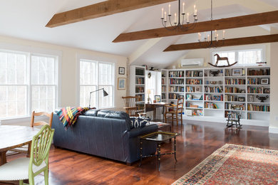 Modelo de sala de estar con biblioteca abierta campestre grande sin chimenea con paredes beige, suelo de madera oscura, suelo marrón y alfombra