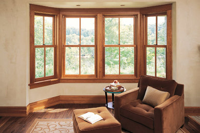 Modelo de sala de estar abierta tradicional de tamaño medio con paredes beige, suelo de madera oscura y suelo marrón