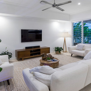 Design ideas for a mid-sized beach style family room in Gold Coast - Tweed with white walls, a wall-mounted tv and beige floor.