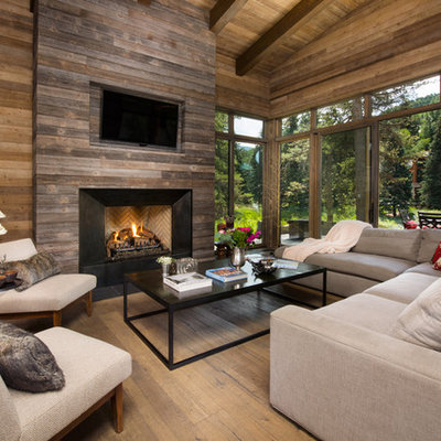Example of a mountain style medium tone wood floor family room design in Denver with brown walls, a standard fireplace and a wall-mounted tv