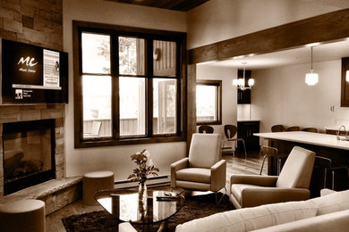 Foto de sala de estar abierta actual de tamaño medio con paredes grises, suelo de madera clara, chimenea de esquina y marco de chimenea de piedra