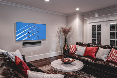 Diseño de sala de estar cerrada contemporánea de tamaño medio con paredes grises, suelo de madera oscura, televisor colgado en la pared y suelo marrón