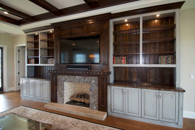 Imagen de sala de estar abierta mediterránea con suelo de madera en tonos medios, todas las chimeneas, marco de chimenea de ladrillo y televisor colgado en la pared