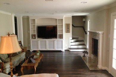 Foto de sala de estar cerrada tradicional de tamaño medio con paredes beige, suelo de madera oscura, todas las chimeneas, marco de chimenea de piedra y televisor independiente