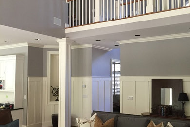 Diseño de sala de estar abierta actual grande con paredes grises, suelo de madera en tonos medios y suelo marrón