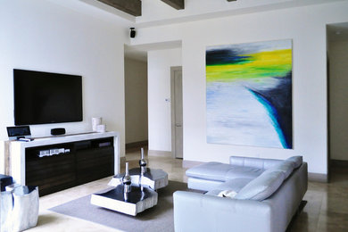 Ejemplo de sala de estar abierta contemporánea pequeña sin chimenea con paredes blancas, suelo de travertino y televisor colgado en la pared