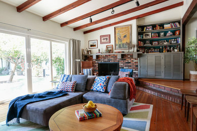 Imagen de sala de estar con barra de bar abierta ecléctica grande con suelo de madera en tonos medios, todas las chimeneas, marco de chimenea de ladrillo y televisor colgado en la pared