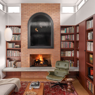 Mittelgroße, Fernseherlose, Offene Retro Bibliothek mit weißer Wandfarbe, Korkboden, Kamin, Kaminumrandung aus Backstein, braunem Boden und Holzdielendecke in Austin