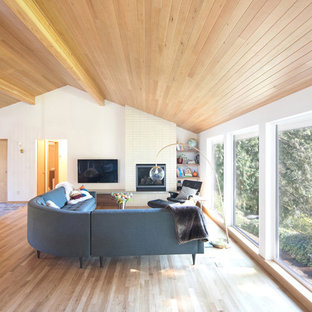 Mittelgroßes, Offenes Retro Wohnzimmer mit braunem Holzboden, Kamin, gefliester Kaminumrandung, Wand-TV, braunem Boden und weißer Wandfarbe in Seattle