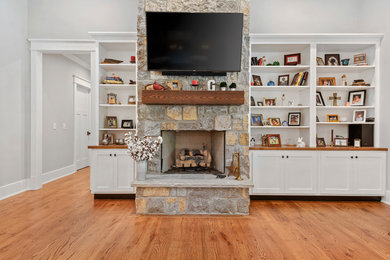 Family room - mid-sized rustic open concept medium tone wood floor and brown floor family room idea in Other with gray walls, a standard fireplace, a stone fireplace and a wall-mounted tv