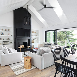 Inspiration pour une salle de séjour rustique ouverte avec un mur blanc, un sol en bois clair, une cheminée standard et un téléviseur fixé au mur.