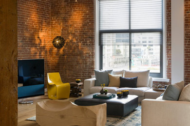 Imagen de sala de estar tipo loft contemporánea grande con televisor independiente, paredes blancas, suelo marrón, ladrillo y suelo de madera clara