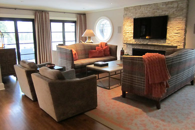 Mittelgroßes, Offenes Klassisches Wohnzimmer mit beiger Wandfarbe, braunem Holzboden, Kamin, Kaminumrandung aus Stein, TV-Wand und braunem Boden in New York