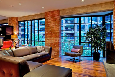 Diseño de sala de estar abierta grande sin chimenea con paredes grises, suelo de madera en tonos medios, televisor colgado en la pared y suelo marrón