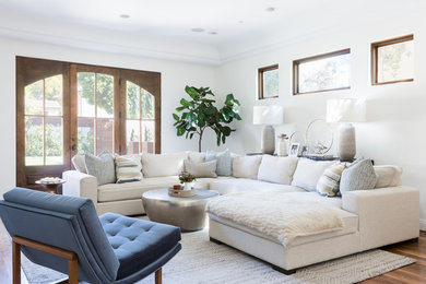 Family room - large mediterranean medium tone wood floor and brown floor family room idea in Los Angeles with white walls