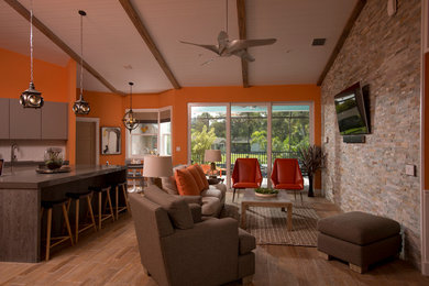 Imagen de sala de estar abierta moderna con parades naranjas, suelo de baldosas de porcelana y televisor colgado en la pared