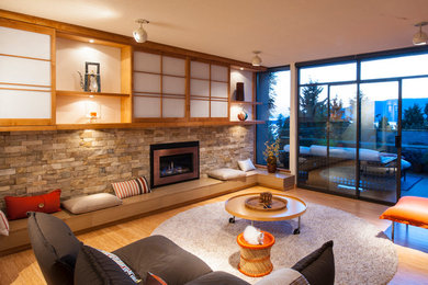 Mid-sized trendy enclosed bamboo floor and beige floor family room photo in Vancouver with white walls, a standard fireplace, a stone fireplace and a media wall