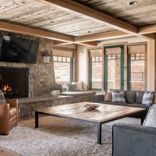 Ispirazione per un grande soggiorno stile rurale con parquet chiaro, pareti beige, camino classico, cornice del camino in pietra, TV a parete e soffitto in legno