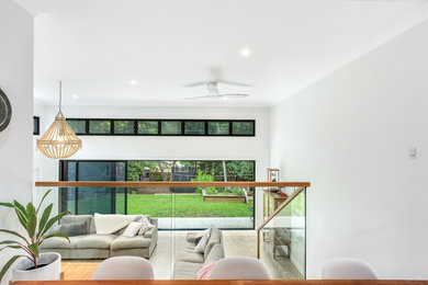 シドニーにあるコンテンポラリースタイルのおしゃれなオープンリビング (白い壁、コンクリートの床、標準型暖炉、コンクリートの暖炉まわり、グレーの床、三角天井) の写真
