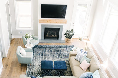 This is an example of a large classic open plan games room in Salt Lake City with grey walls, medium hardwood flooring, a standard fireplace, a concrete fireplace surround and a wall mounted tv.