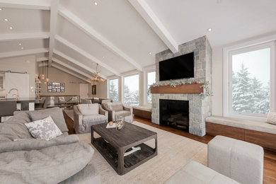 Imagen de sala de estar abierta tradicional renovada grande con paredes blancas, suelo de madera en tonos medios, todas las chimeneas, marco de chimenea de piedra y televisor colgado en la pared
