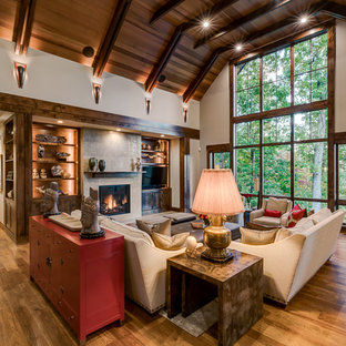 Example of a mountain style medium tone wood floor family room design in Other with beige walls, a standard fireplace and a media wall