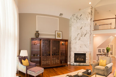 Großes, Offenes Klassisches Wohnzimmer mit braunem Holzboden, Eckkamin, Kaminumrandung aus Stein, verstecktem TV, grauer Wandfarbe und braunem Boden in Philadelphia