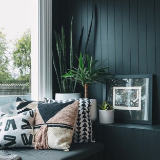 Modernes Wohnzimmer mit schwarzer Wandfarbe, gebeiztem Holzboden, Kaminofen, Kaminumrandung aus Metall, rosa Boden und vertäfelten Wänden in Sonstige