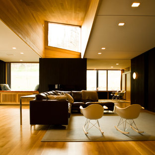 Aménagement d'une grand salle de séjour moderne ouverte avec un mur noir, un sol en bois clair, aucune cheminée et aucun téléviseur.