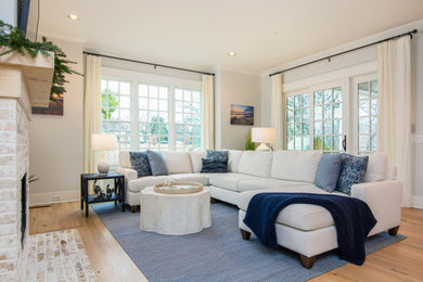 Modelo de sala de estar costera con paredes grises, suelo de madera en tonos medios y suelo marrón