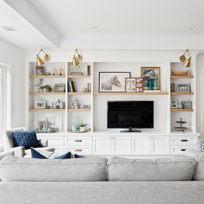 Example of a large beach style open concept light wood floor and brown floor family room design in San Francisco with white walls, no fireplace and a media wall