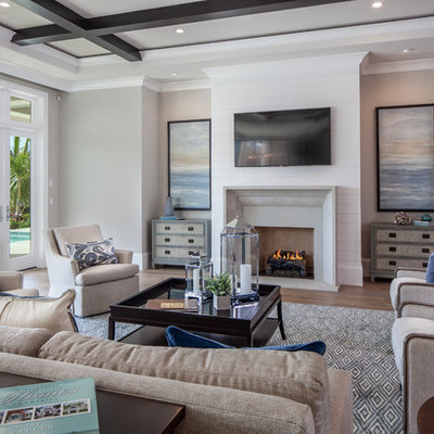 Family room - transitional open concept light wood floor family room idea in Miami with gray walls, a standard fireplace and a wall-mounted tv