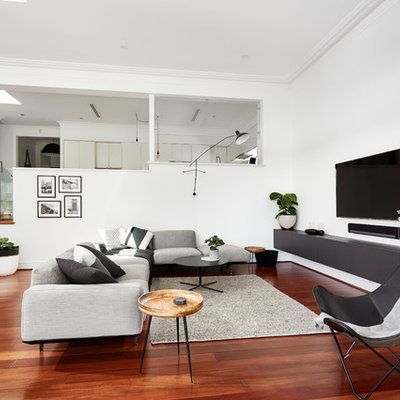 Mid-sized trendy medium tone wood floor and red floor family room photo in Perth with white walls, no fireplace and a wall-mounted tv