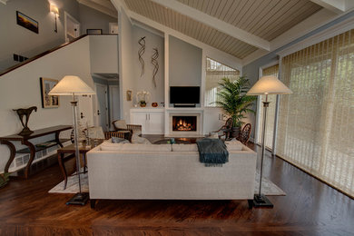 Photo of a large beach style enclosed games room in San Francisco with grey walls, dark hardwood flooring, a standard fireplace, a tiled fireplace surround and a wall mounted tv.