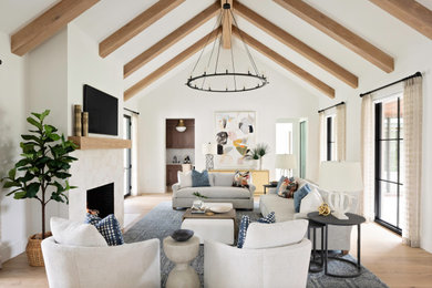 Huge transitional open concept light wood floor, exposed beam, vaulted ceiling and beige floor family room photo in Orlando with white walls, a standard fireplace, a tile fireplace and a wall-mounted tv