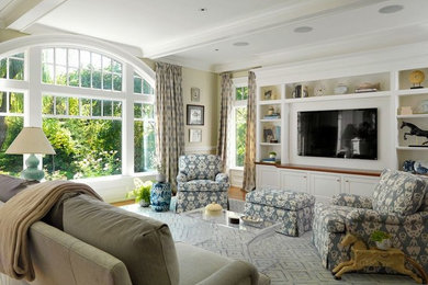 Diseño de sala de estar tradicional con paredes beige, suelo de madera clara y pared multimedia