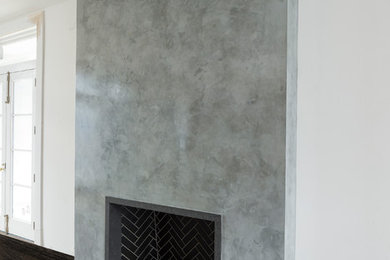 Imagen de sala de estar abierta contemporánea pequeña con marco de chimenea de yeso y televisor colgado en la pared