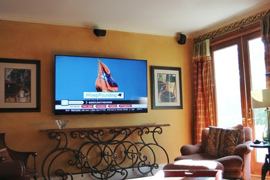 Cette photo montre une salle de séjour chic avec un mur orange et un téléviseur fixé au mur.