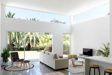 Foto de sala de estar abierta marinera sin chimenea con paredes blancas, suelo de cemento, televisor independiente y suelo gris