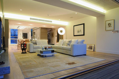Esempio di un soggiorno minimal di medie dimensioni e aperto con pareti bianche, parquet chiaro e TV a parete