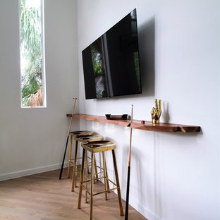 Example of a large trendy enclosed light wood floor game room design in Los Angeles with white walls and a wall-mounted tv